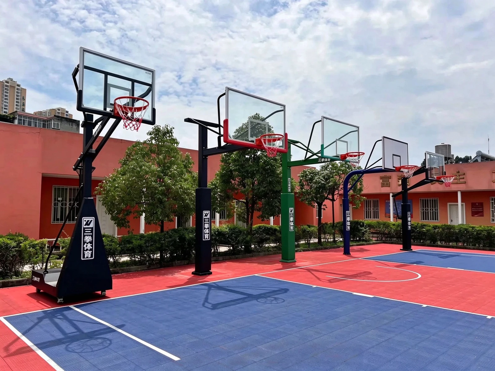 Five basketball hoop systems arranged on an outdoor sports court.