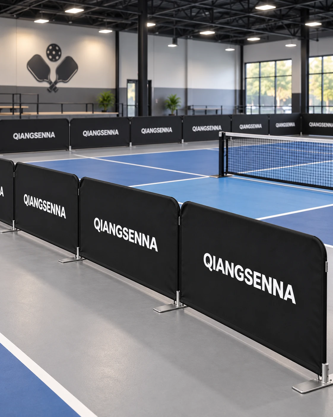 Black modular court barriers around an indoor pickleball court