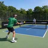 Black QIANGSENNA barriers beside players on an outdoor pickleball court