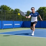 Blue QIANGSENNA barriers beside an outdoor pickleball player